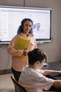 Educator stands with a student in a modern classroom environment.