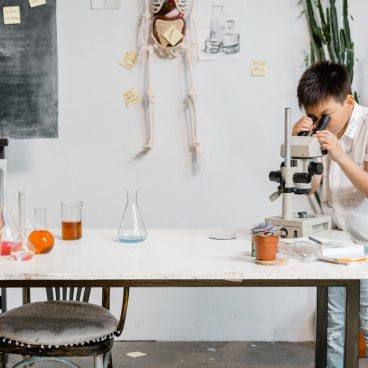 A young boy in a laboratory examining samples through a microscope for educational purposes.